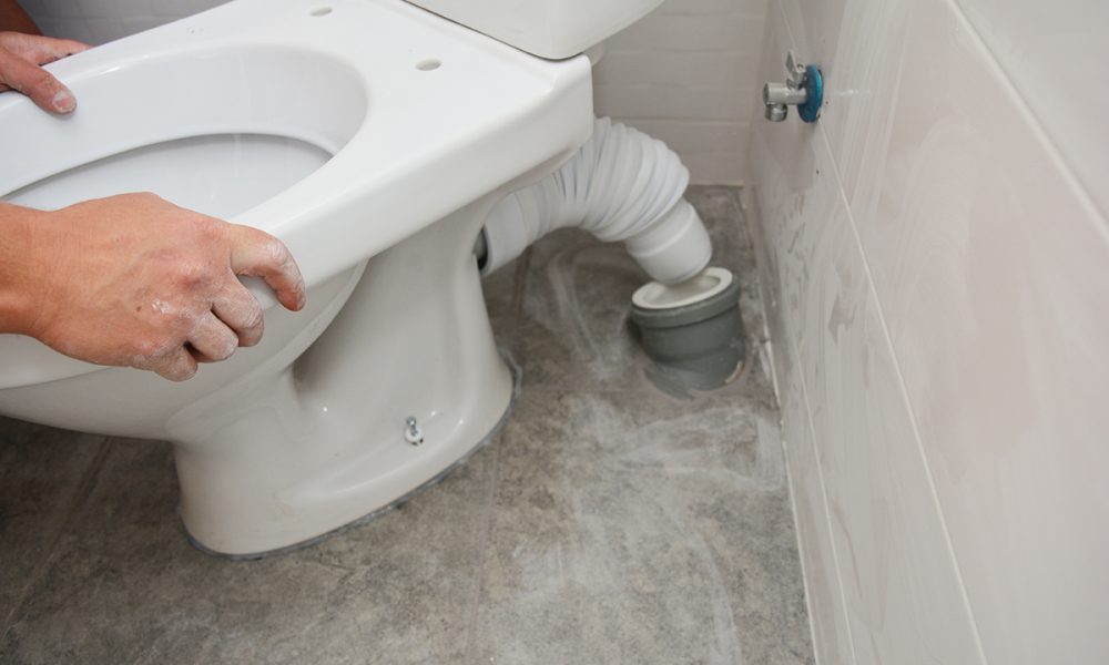 Handyman installing flush toilet. Repairing, dismantling toilet bowl in the bathroom